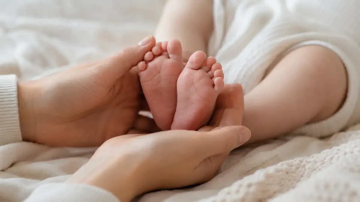 Manos de un adulto sosteniendo los piecitos de un bebé